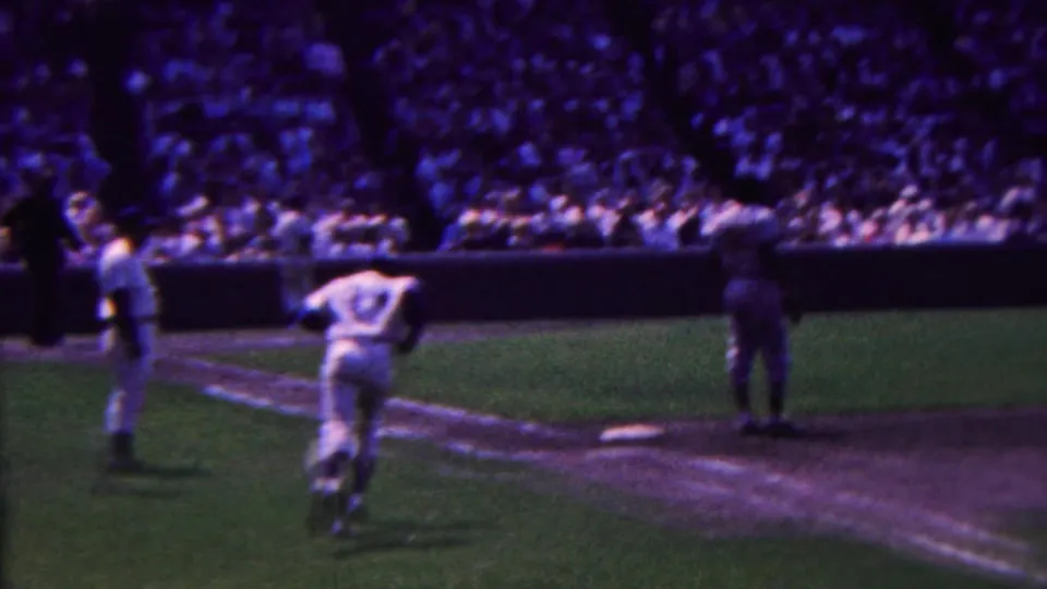 In the final frame, a baseball player wearing number 14 runs across the infield as another player stands near the base path and spectators fill the stands.