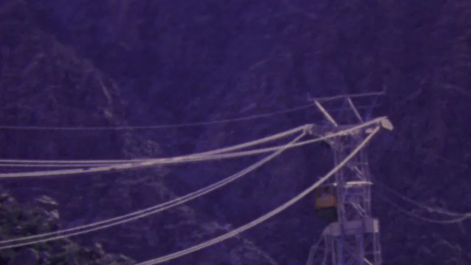 The aerial tramway car hangs near the support structure as cables stretch across the frame in purple-shifted 8mm footage from Palm Springs.