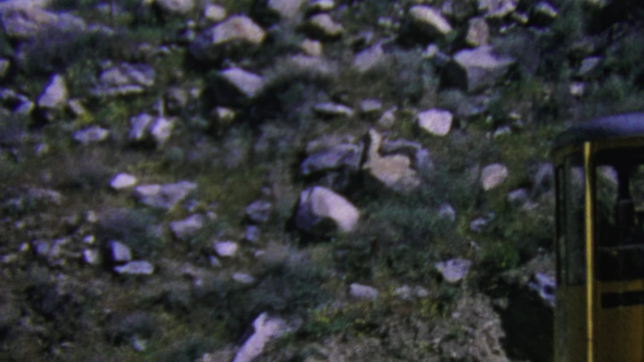 A yellow aerial tramway car appears along a rocky Palm Springs mountain slope in 1964 8mm home-movie footage.