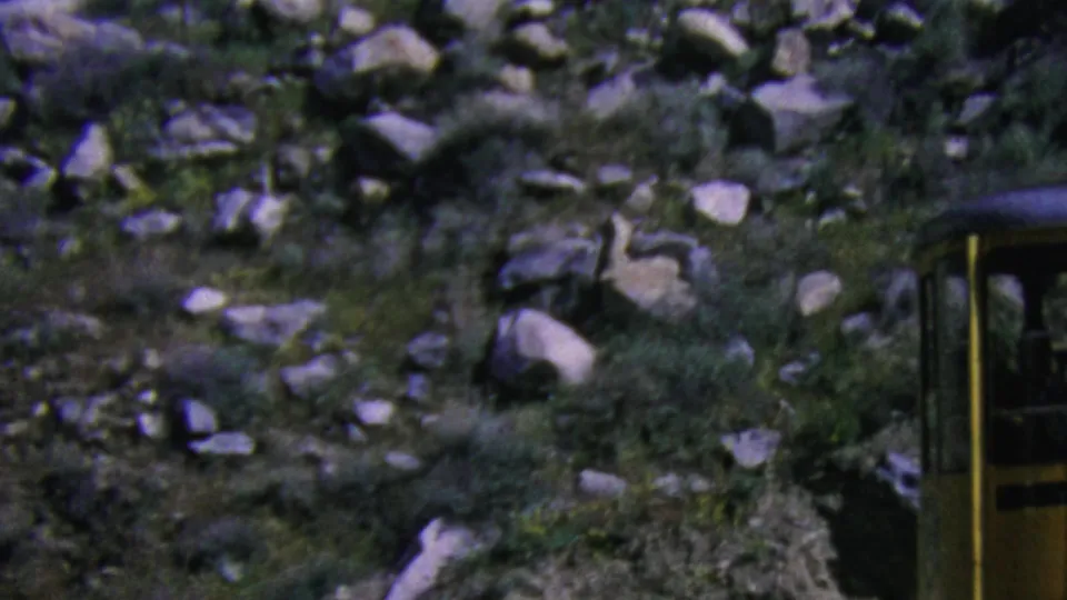 A yellow aerial tramway car appears along a rocky Palm Springs mountain slope in 1964 8mm home-movie footage.