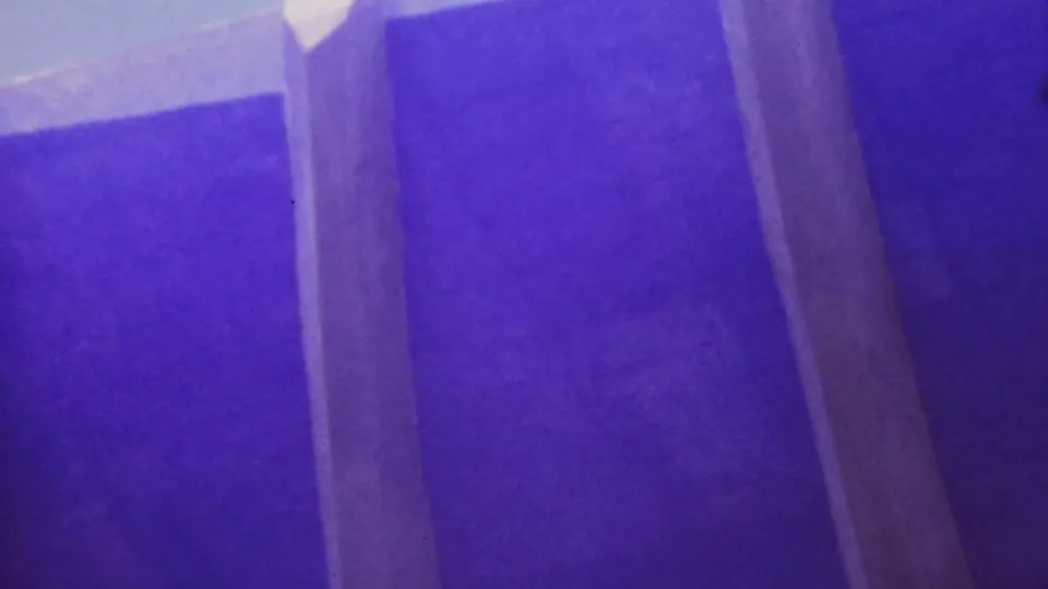 Low-angle 1964 Honolulu home-movie view beneath a bridge or elevated roadway, showing concrete pillars, underside beams, and pale sky openings through a blue-violet 8mm scan.