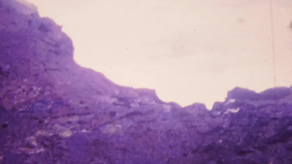 1964 Honolulu 8mm frame looking across a rough rocky cliff edge toward overexposed white surf or spray below.