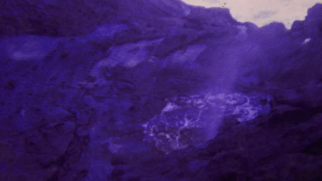 Bright white spray or foam appears on dark rocky terrain.