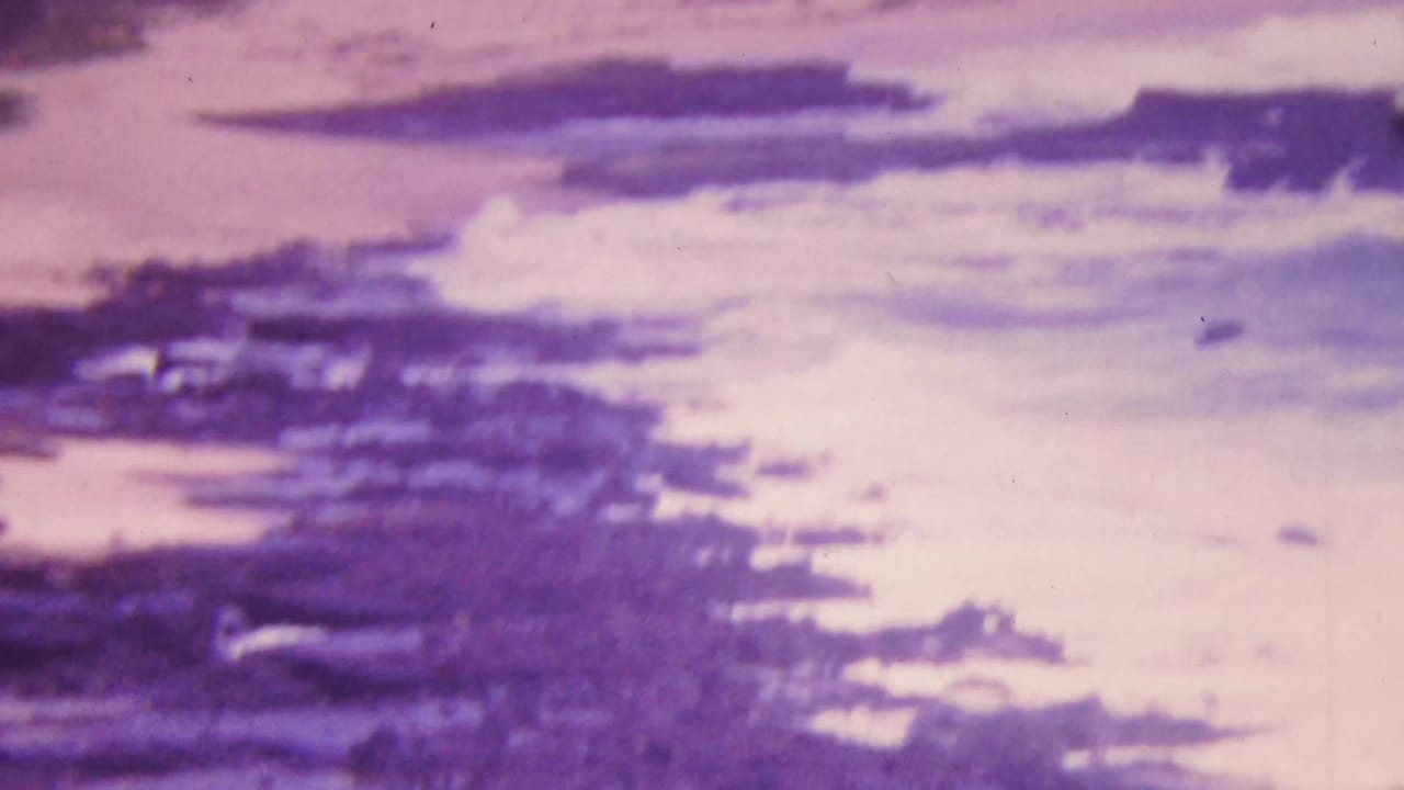 A Honolulu coastal reef appears through aged 8mm color shift as white surf breaks across dark rock formations.