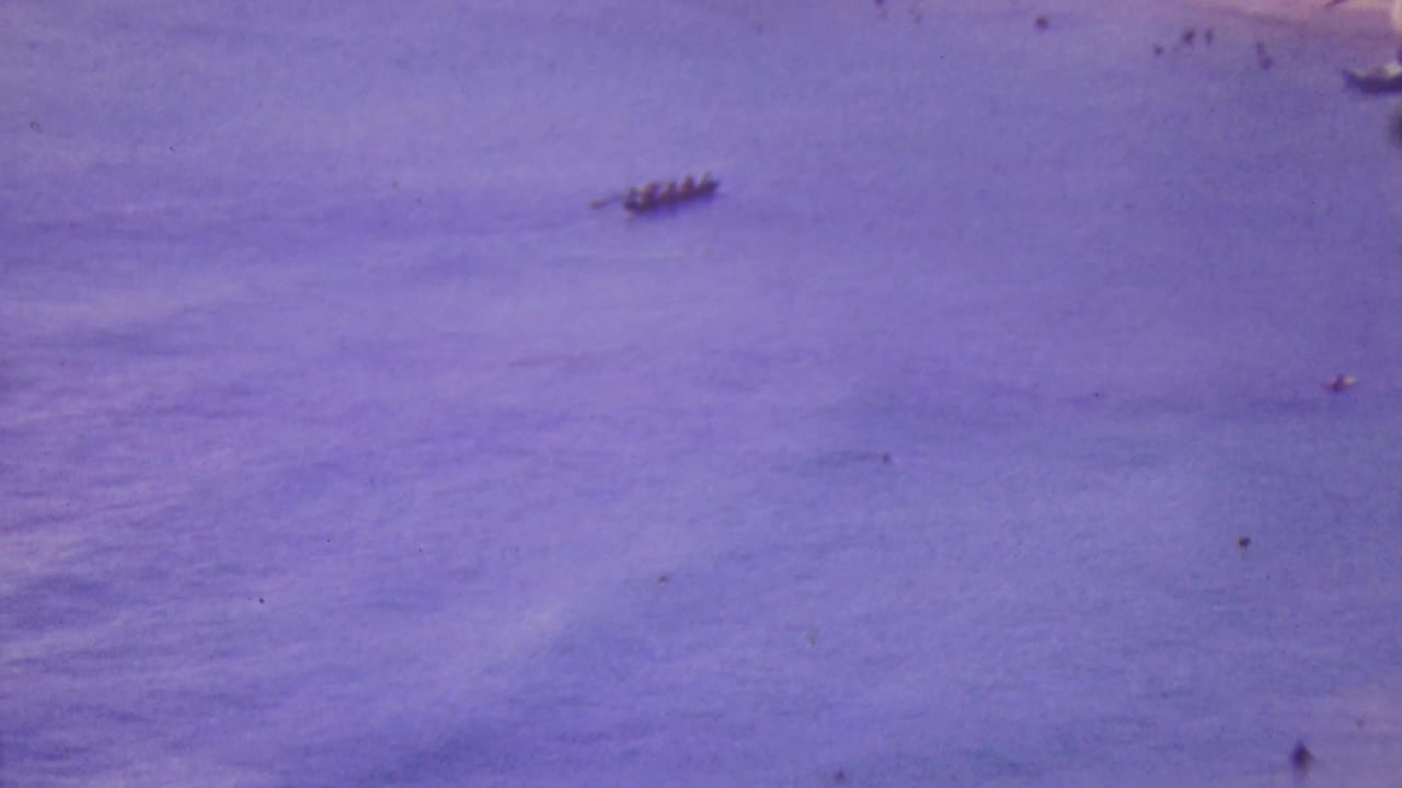 Distant small boats on purple-tinted ocean water.