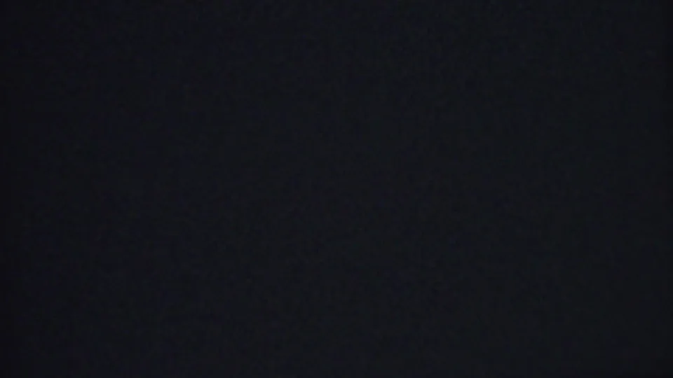Final near-black frame from the 8mm clip, retaining slight film grain and a dim blue-black cast after the ocean scene fades out.