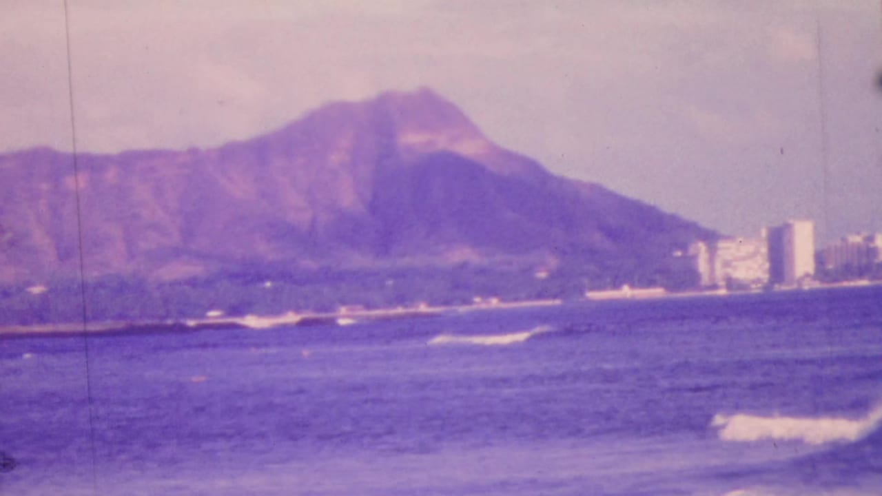 Diamond Head and Honolulu shoreline viewed over choppy blue water.