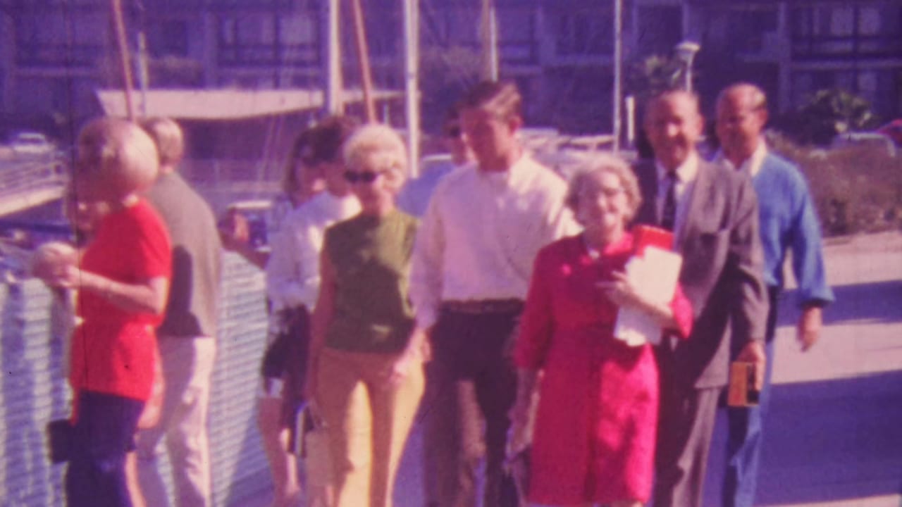 Group of adults in dress clothes walking beside a marina railing.