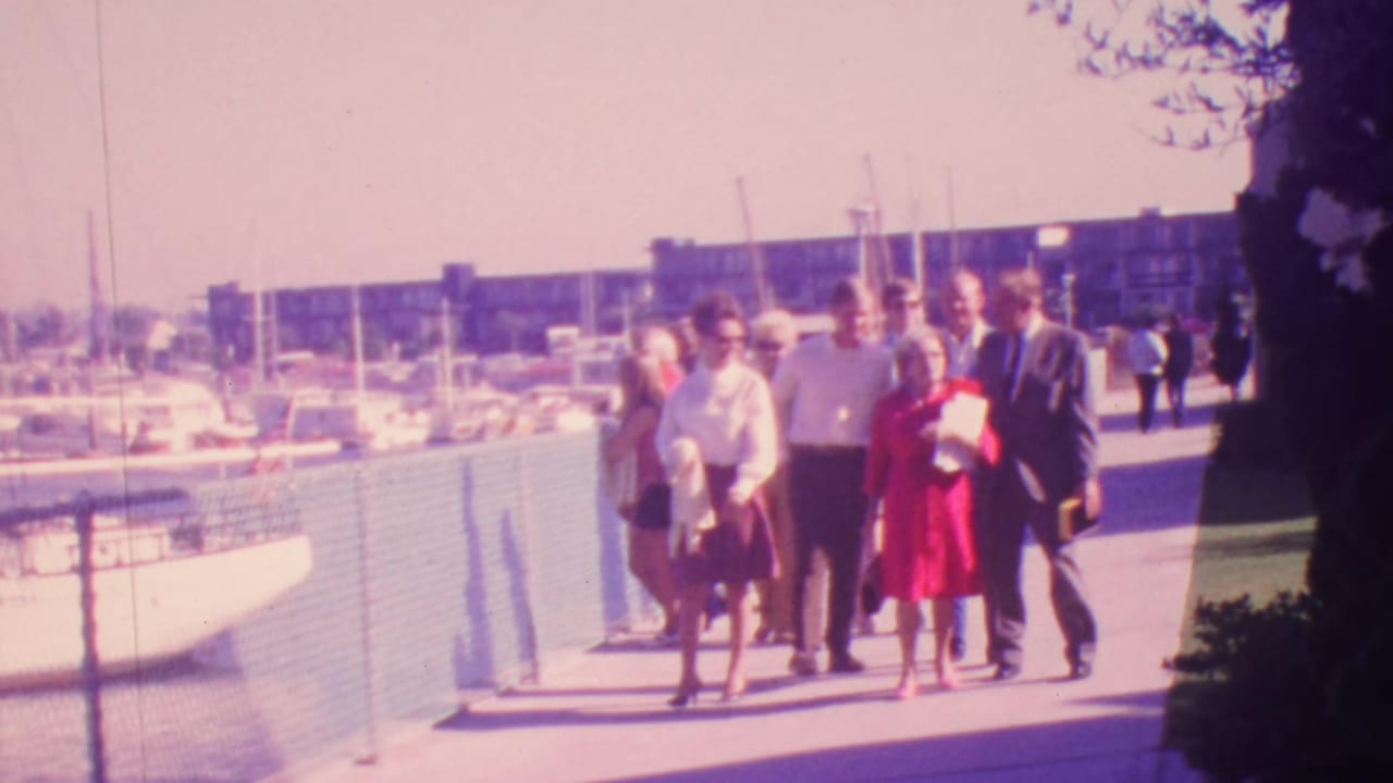 Group of adults on a waterfront walkway with marina boats behind them.