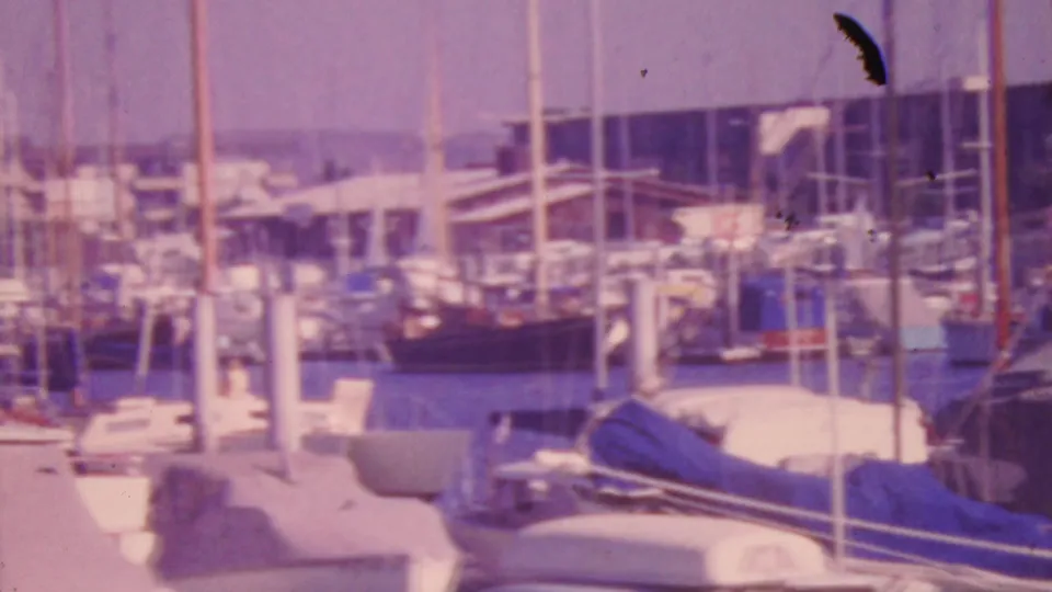 Faded 8mm view of a 1964 Honolulu marina with layered masts, dock pilings, harbor water, and a covered boat near the foreground.