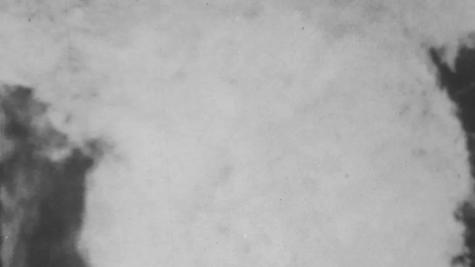 Blurred 8mm frame from the 1962 Honolulu flood footage, dominated by pale turbulent water with a dark foreground edge at left.