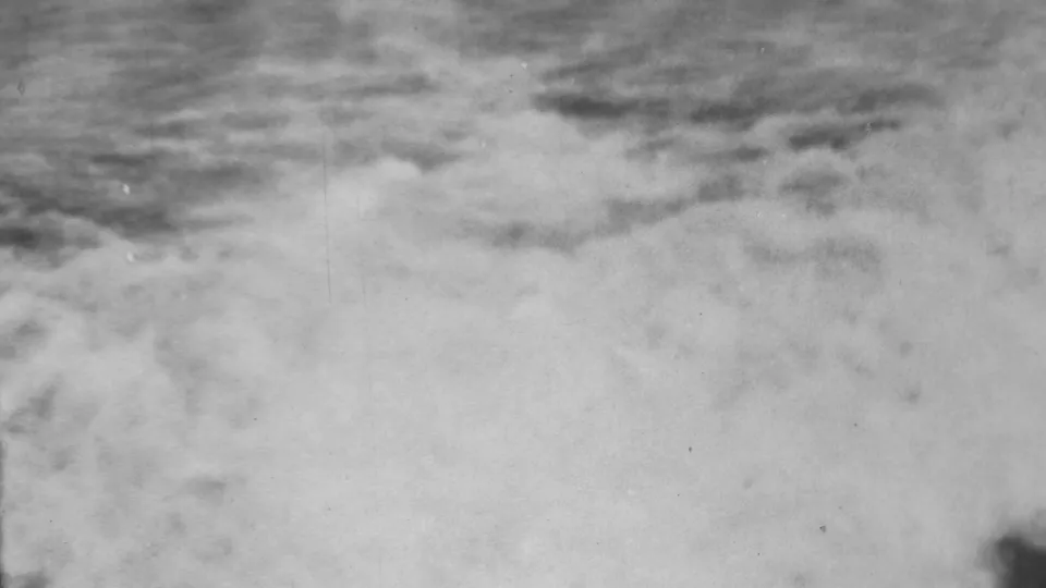 1962 Honolulu-area flood footage frame showing churning water and a dark vertical edge or obstruction, with little background detail visible.