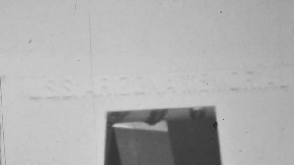 Black-and-white 1962 Pearl Harbor frame showing the lower portion of a bright concrete structure and a dark recessed entrance area with indistinct shadowed forms.
