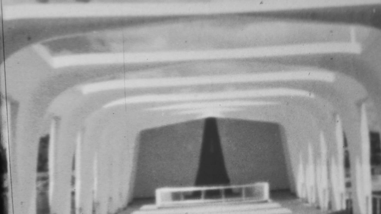 Arched tunnel-like interior with bright ceiling bands and a dark curtain at the far end.