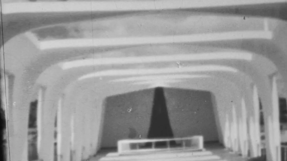 1962 Pearl Harbor-area home-movie frame with the arched interior centered, showing the dark curtain, low foreground rail, curved ceiling bands, and side openings.