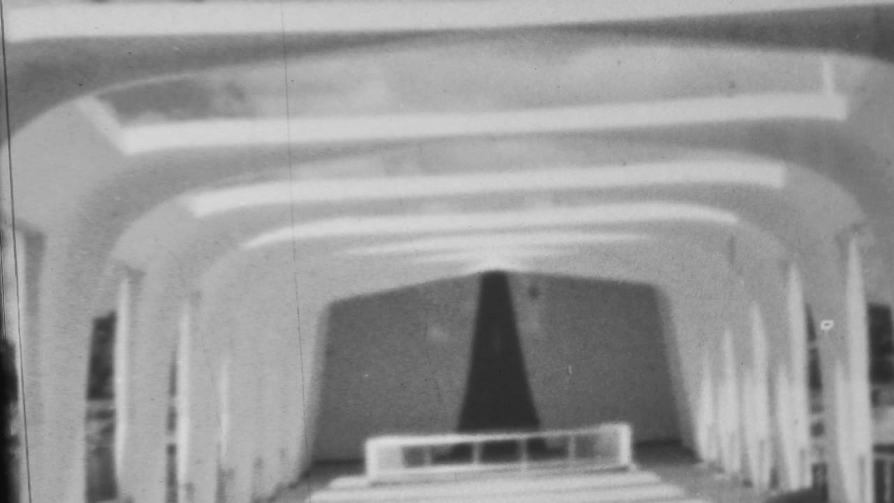 1962 Pearl Harbor-area 8mm frame showing a curved arched interior or monument passage with a dark central sculpture or marker at the far end.