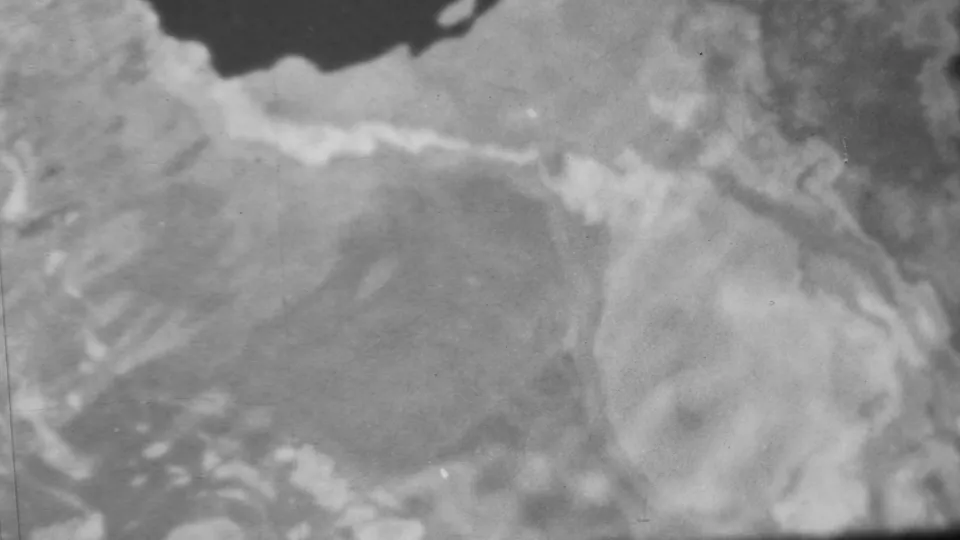 1962 Honolulu-attributed 8mm frame showing abstract shoreline water patterns with pale foam-like areas, wet rock edges, and visible film grain.
