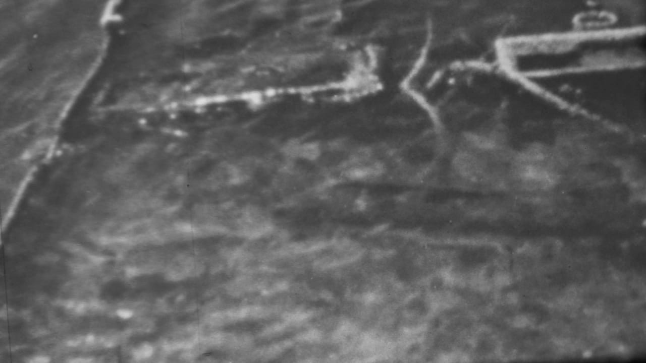 1962 Pearl Harbor, Honolulu 8mm frame showing a soft high-angle black-and-white view of pale surf, dark water, and apparent wreckage near the shoreline.