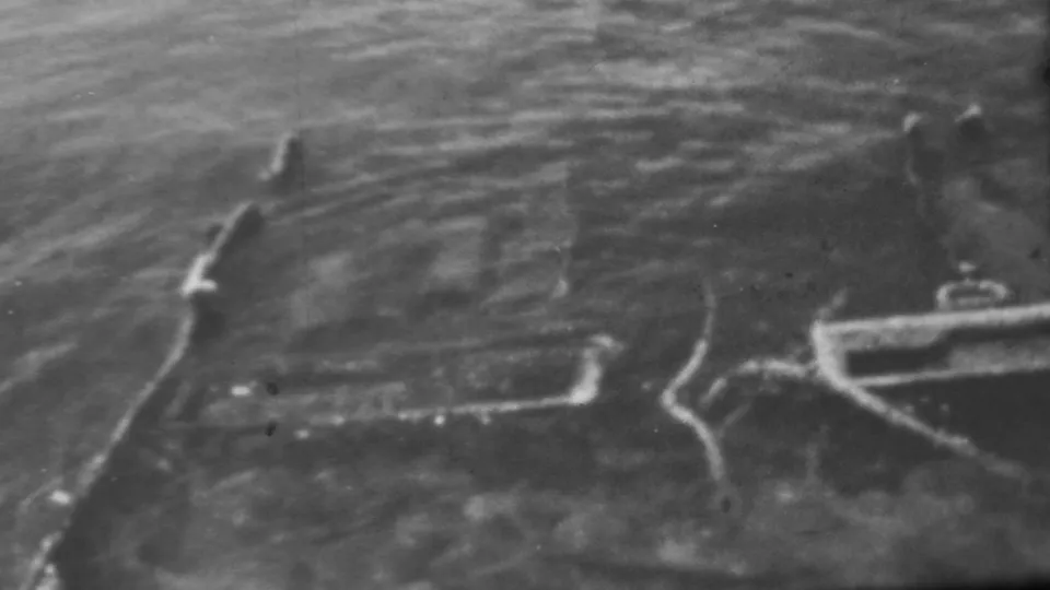 1962 Pearl Harbor, Honolulu frame with soft black-and-white waves, dark water, and light-toned wreckage-like lines at the shoreline.