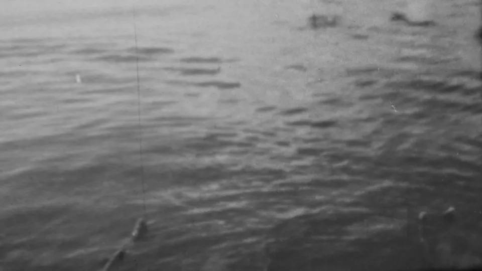 Grainy 8mm frame from Pearl Harbor showing rippling water, a small dark protrusion, and barely visible submerged forms.
