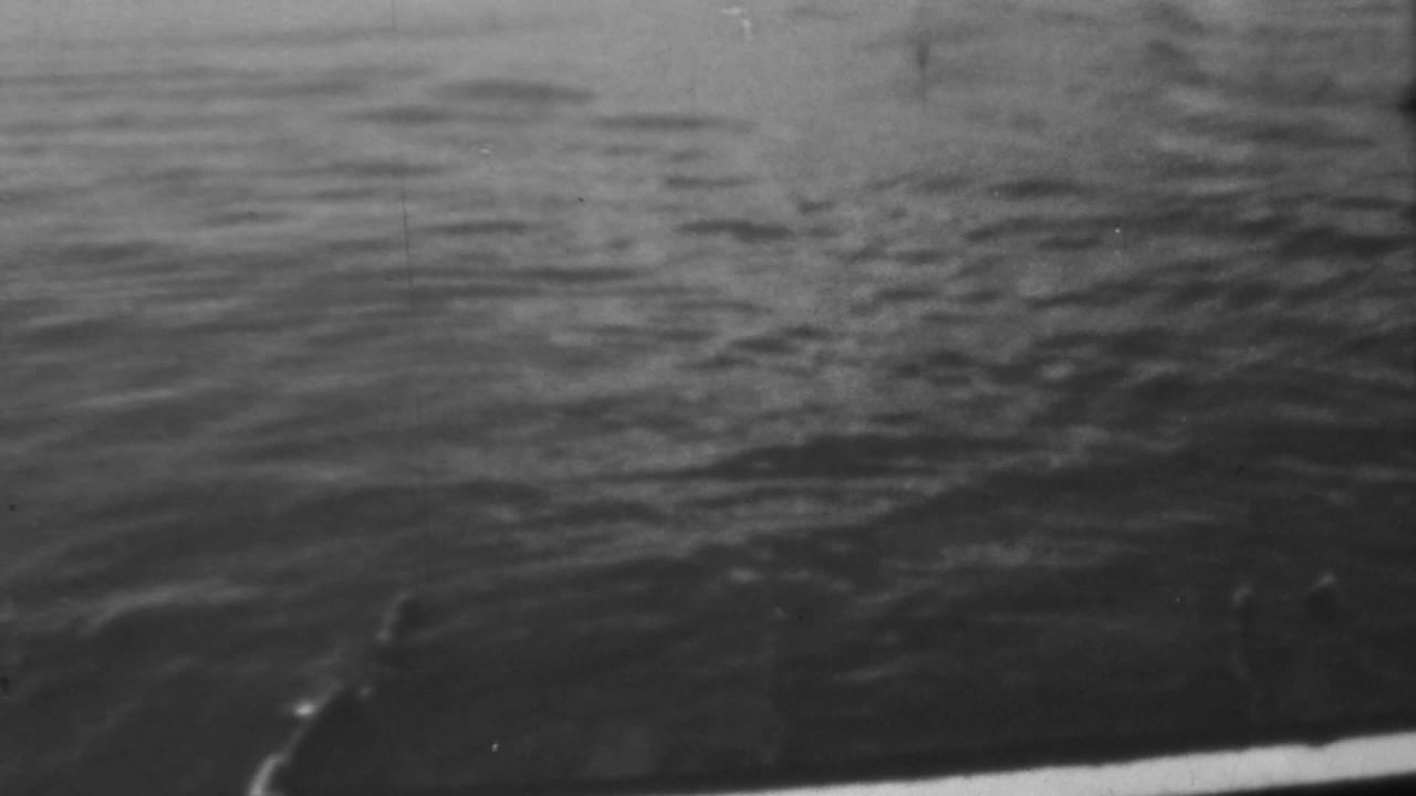 A 1962 Pearl Harbor home-movie frame appears to show harbor water filmed from a vessel, with the ship edge cutting across the lower part of the frame.