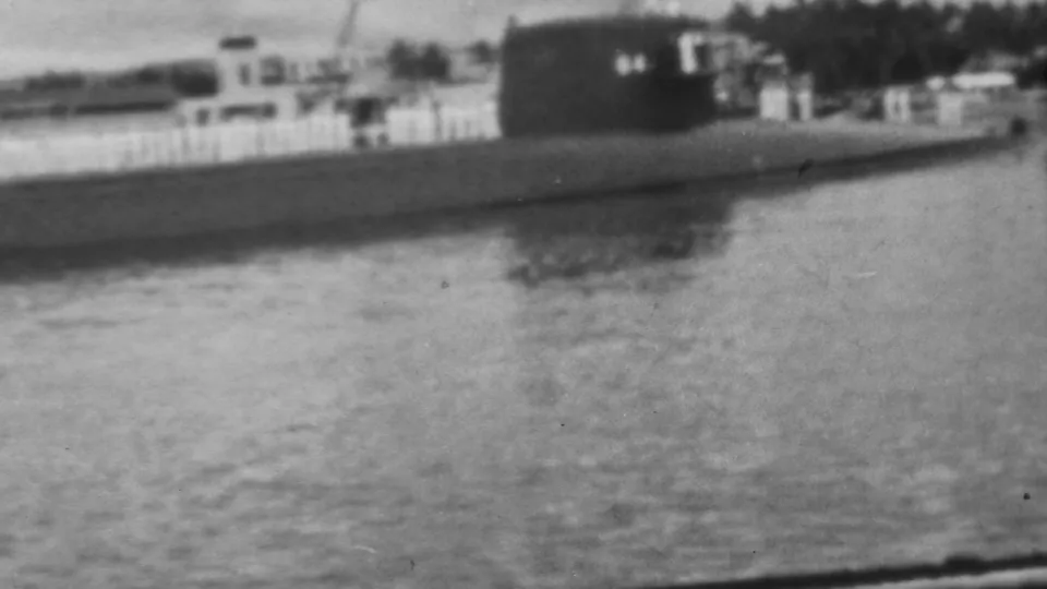 Pearl Harbor home-movie frame showing a large dark naval-looking vessel passing near the USS Arizona Memorial area in 1962.
