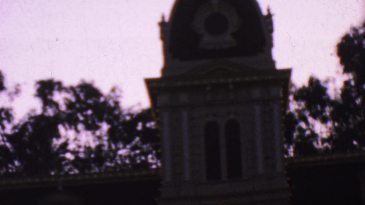 Dark tower and roofline of the Disneyland City Hall building against trees.