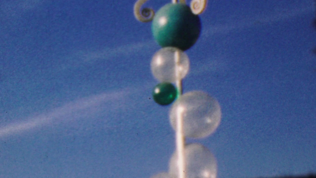 Vertical pole with green and translucent spheres, with white scroll details near the top.