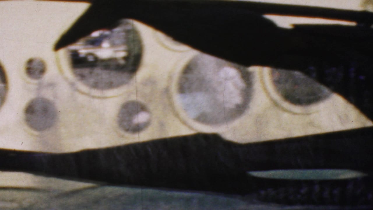 Frame from the 1964 Anaheim clip with rounded glass windows, pale molded surfaces and dark aircraft-like silhouettes cutting across the view.