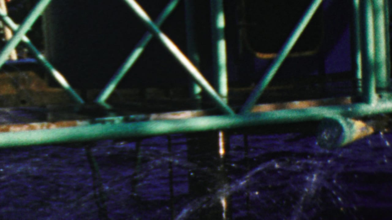 Dark ride structure and green railings above splashing water, with porthole details partially visible.