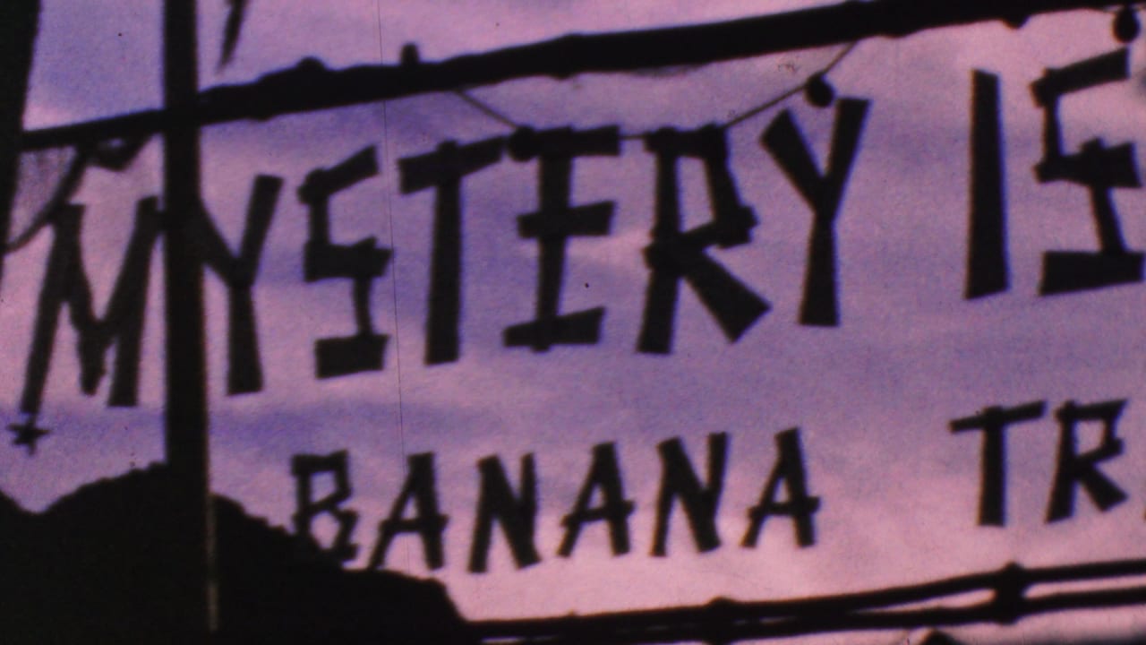 1964 Anaheim home-movie frame showing dark hand-painted Mystery Island and Banana Train lettering on a pale sign backing with silhouetted edges.