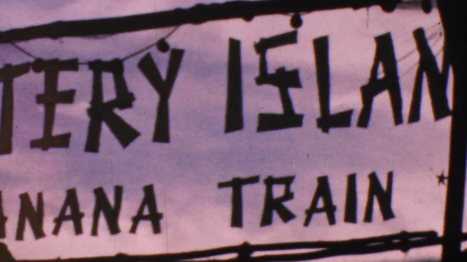 1964 Anaheim frame of the Mystery Island sign, with Banana Train text below, decorative hanging elements, and soft 8mm color shift.