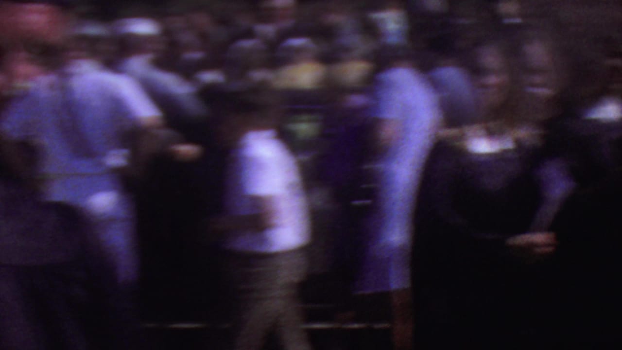 Blurred crowd movement with graduates and visitors crossing the frame.