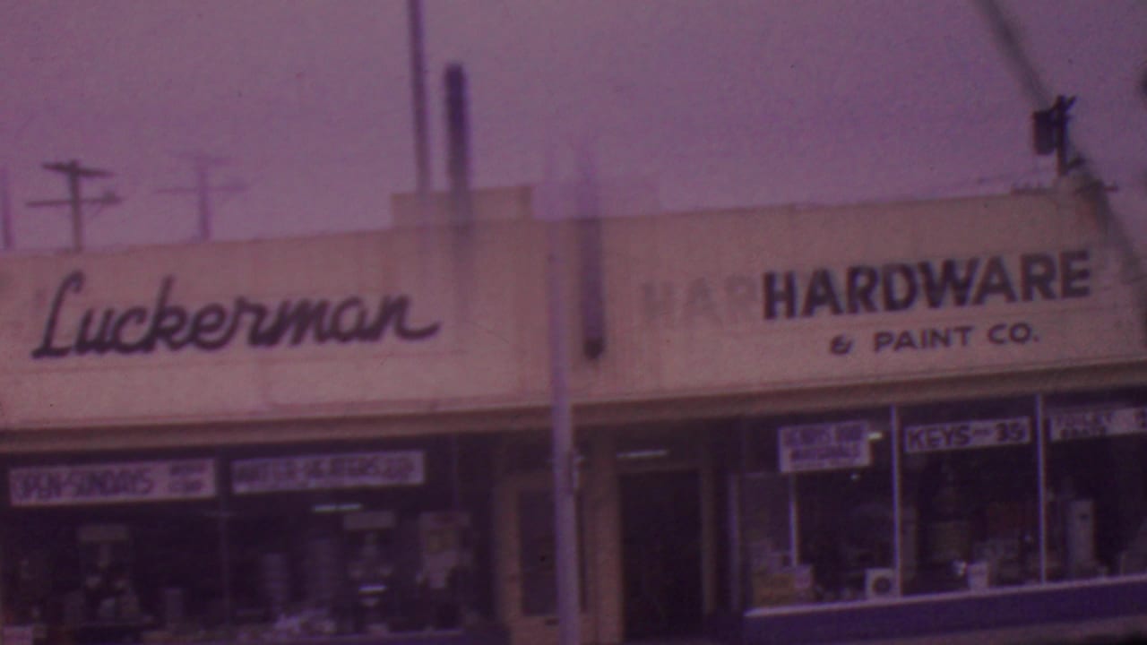 The Luckerman name appears on a white commercial facade in Los Angeles, with hardware and paint signage, glass windows, and street utilities visible in the 8mm frame.
