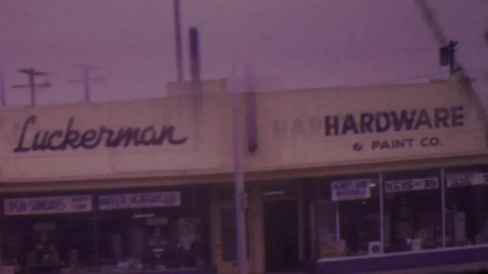 The Luckerman name appears on a white commercial facade in Los Angeles, with hardware and paint signage, glass windows, and street utilities visible in the 8mm frame.