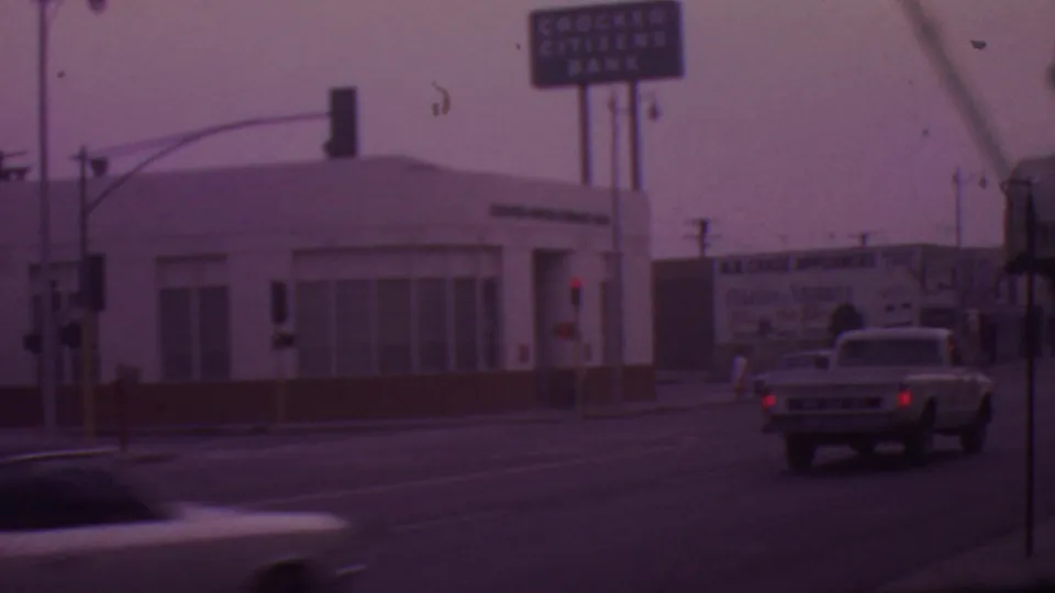 A classic pickup truck drives through a Los Angeles intersection near the Crocker Citizens Bank building, traffic lights, and a B.B. Chase Appliances billboard.