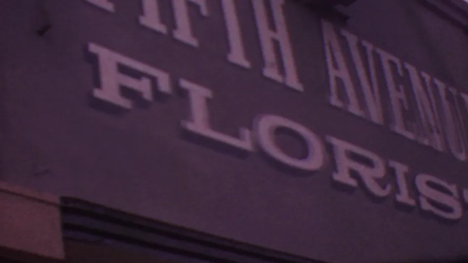 1965 Los Angeles 8mm close-up of a dark storefront sign with raised white lettering for FIFTH AVENUE FLORIST.