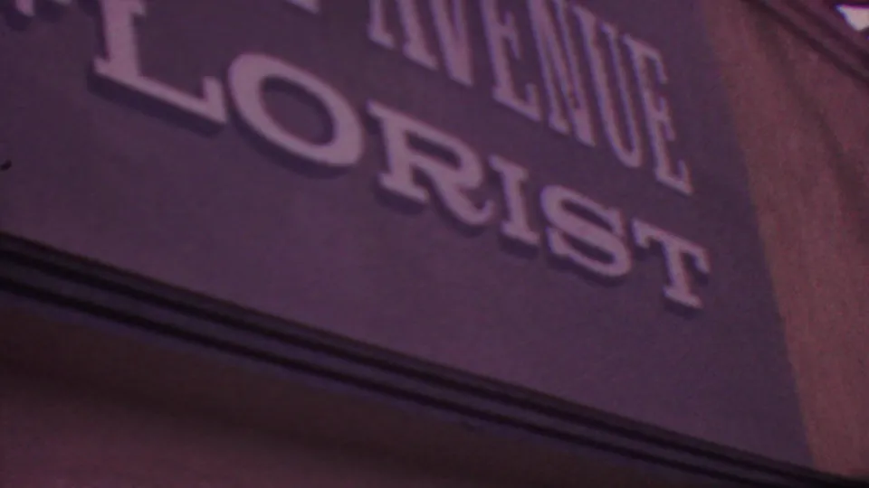 Final close 1965 Los Angeles frame on the dark Fifth Avenue Florist sign, with the FLORIST lettering partly cropped by the edge of the shot.