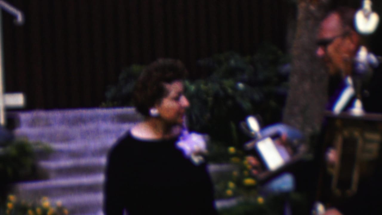 Woman turns toward a large trophy during an outdoor award presentation.