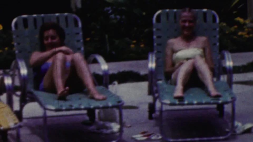 The women appear on separate green metal loungers in a sunlit California poolside setting, framed by the soft grain and color fade of 1961 8mm film.