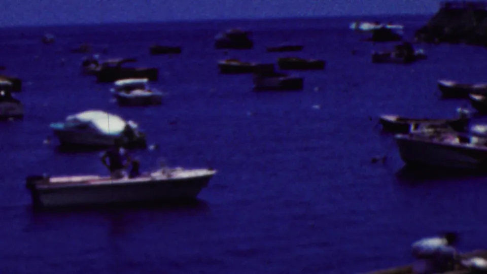 Several small boats appear on blue waterfront water in a brief California home-movie cutaway from the 1961 clip metadata.