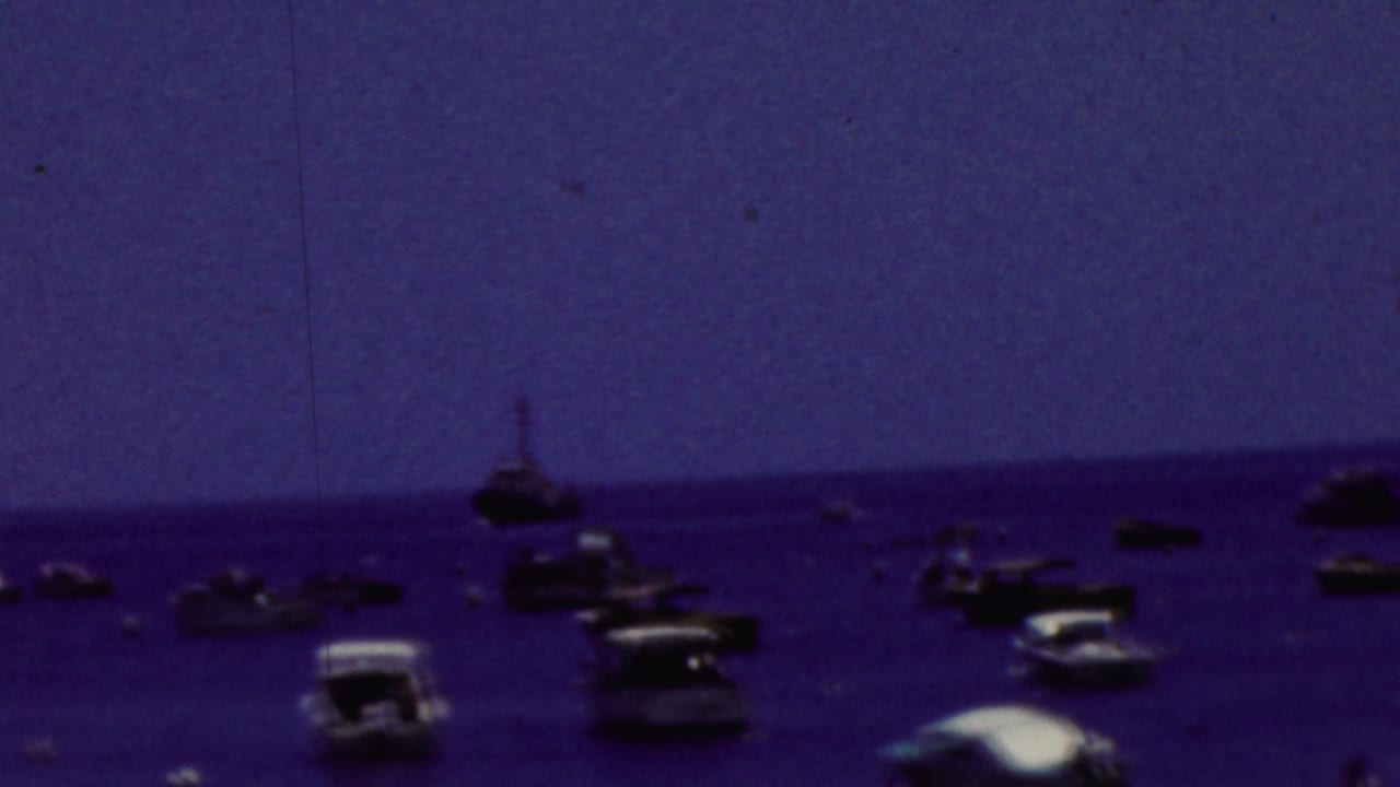 Distant motorboats and small craft spread across calm water.