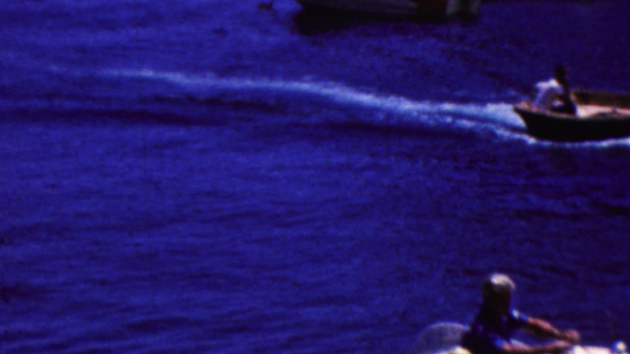 A small motorboat moves across deep blue water in 1961 California home-movie footage, leaving a bright wake behind it.