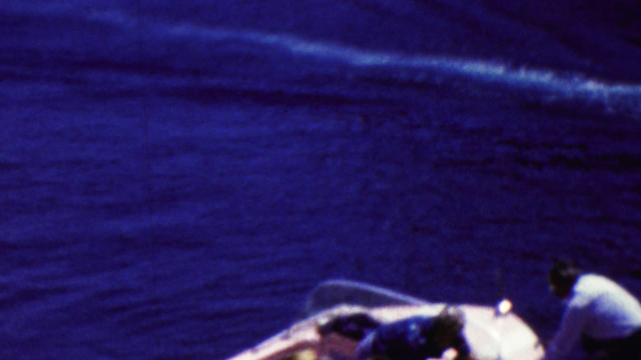 Motorboat on blue water with part of another boat and people at the lower edge.