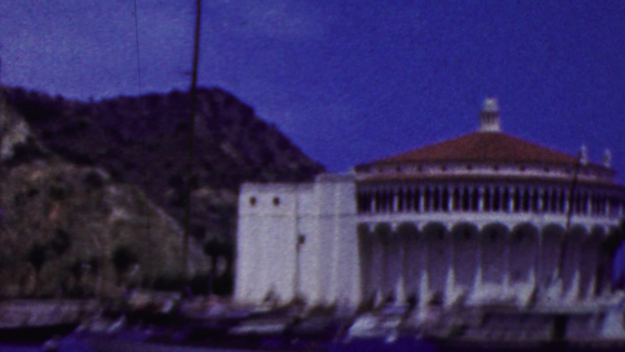 1961 8mm view of the Santa Catalina Island Casino in California from the water, with the white circular building framed against a dark hillside.