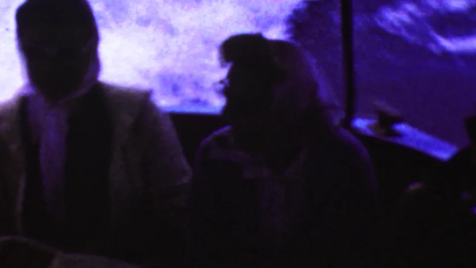 Two adult passengers appear in silhouette inside the boat, backed by bright purple-blue reflected light in this 1961 California 8mm frame.