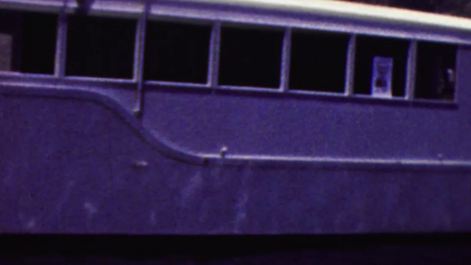 1961 California 8mm frame showing a closer side view of the white motorboat, its long row of dark cabin windows, curved trim line, and water below.