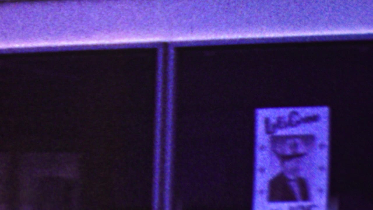 Bus window section with a poster visible against a dark interior.