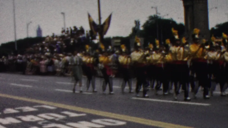 1961 California parade frame with uniformed Kentucky band members, a visible bass drum, tall plumes, and crowds watching from the sidewalk.
