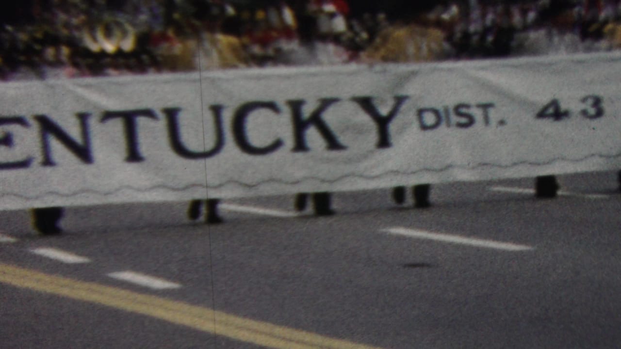 A low-angle 8mm view shows the Kentucky District 4.3 Lions banner moving along the parade route, with marchers mostly obscured by the cloth.
